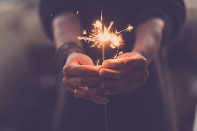 Close-up of person holding sparkler at night