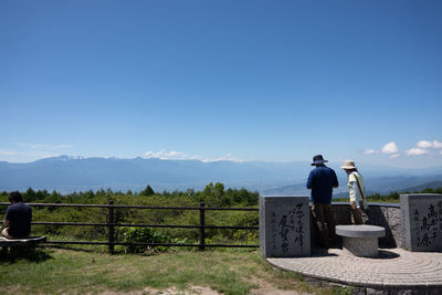 Rear view of man standing on mountain against sky