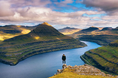 Rear view of man standing on mountain against sky