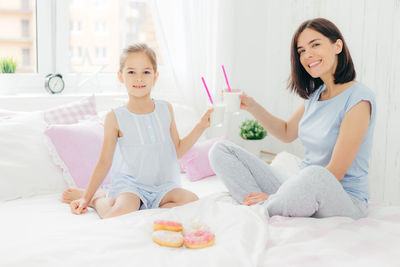 Happy young woman sitting on bed at home