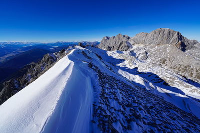 Scenic view of snowcapped dachstein massiv mountains against clear blue sky