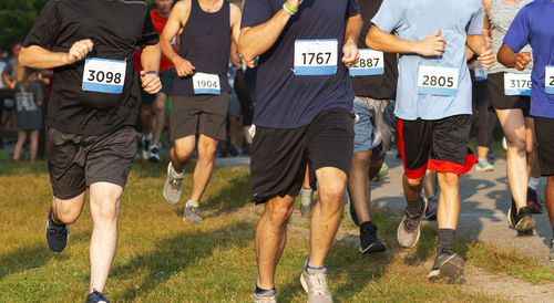 Runners running a 5k race on grass in during a very crowded event.