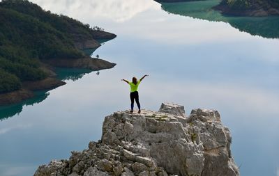 Man standing on rock by mountain against sky