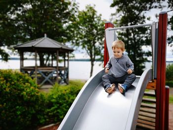 Portrait of boy sitting on slide at playground
