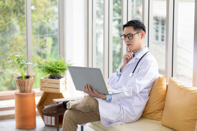 Midsection of man using mobile phone while sitting on table