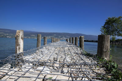 Pier over sea against clear blue sky