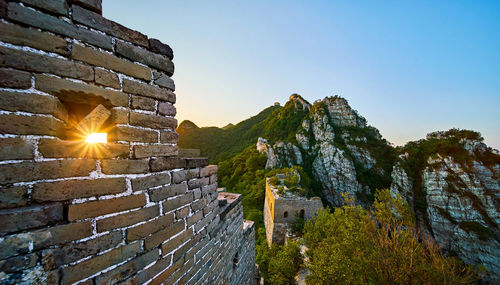 Great wall of china by mountain against sky during sunrise