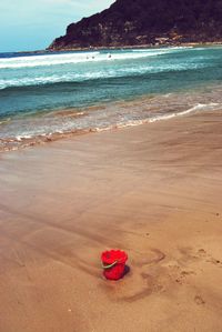 Red umbrella on beach against sky