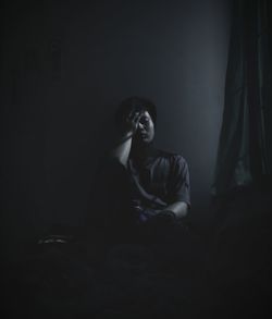Depressed man sitting in darkroom