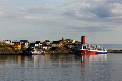 Sailboats in sea by buildings against sky