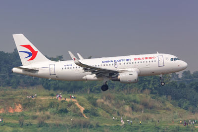 Airplane flying over land against sky