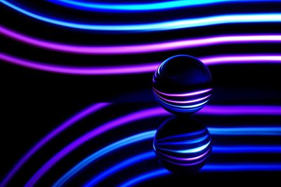 Close-up of crystal ball and illuminated lights against black background