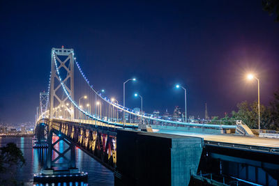 Illuminated bridge against sky at night