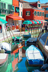 Boats moored in canal by buildings in city