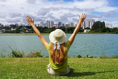 Rear view of woman with arms raised standing on field in curitiba, brazil