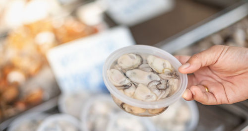 Female customers choose fresh raw shellfish seafood in the plastic box from the retail market store.