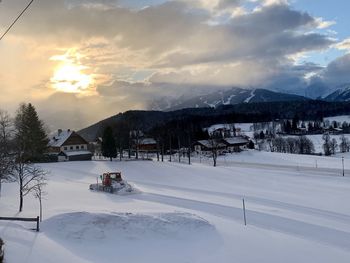 Snow covered houses by buildings against sky during winter