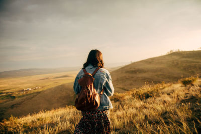 Rear view of woman standing on field against sky