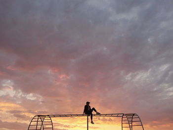 Silhouette man standing by railing against sky during sunset