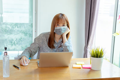 Woman using phone while sitting on table