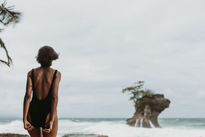 Rear view of shirtless man looking at sea against sky