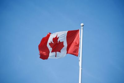 Low angle view of canadian flag against blue sky