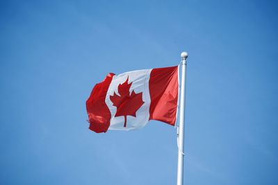 Low angle view of flag against blue sky