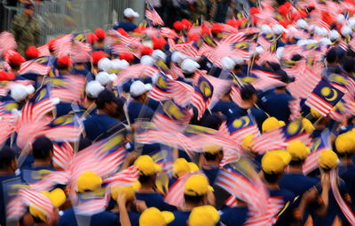 Group of people holding malaysian flag during parade