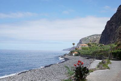 Scenic view of mountains at sea shore against sky