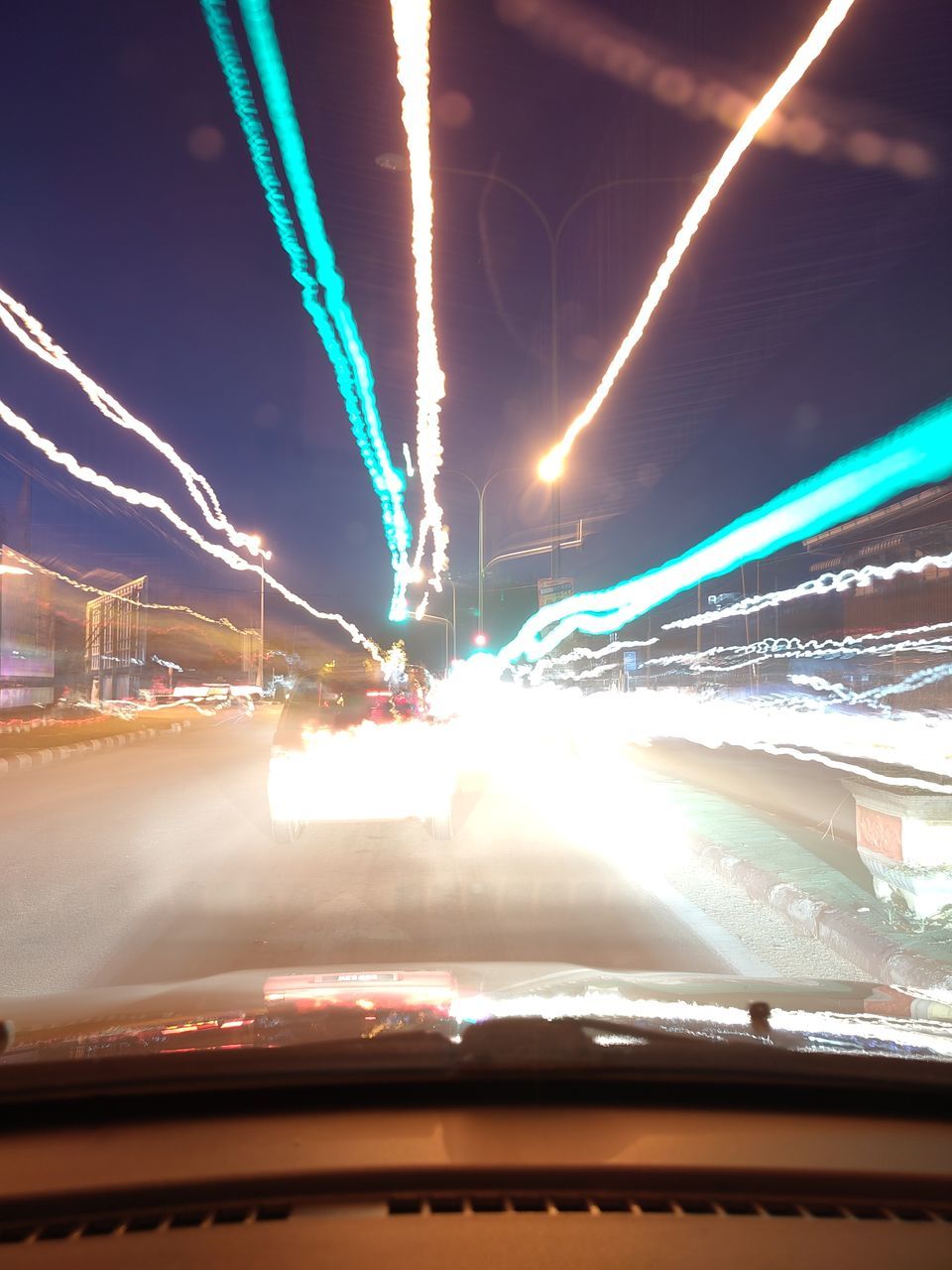 ILLUMINATED LIGHT TRAILS ON STREET IN CITY AT NIGHT