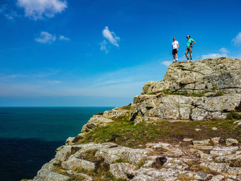 Standing on rock by sea against sky