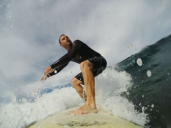 Man surfing in sea against sky