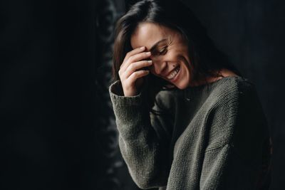 Portrait of smiling young woman against black background