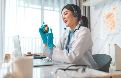 Side view of a smiling young woman sitting on table