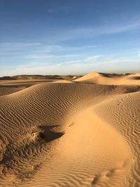 Sand dunes in desert against sky