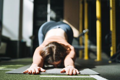 Young brunette woman doing stretching pilates, practice yoga on mat in fitness club gym