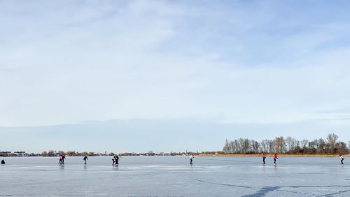 People on snow covered landscape against sky