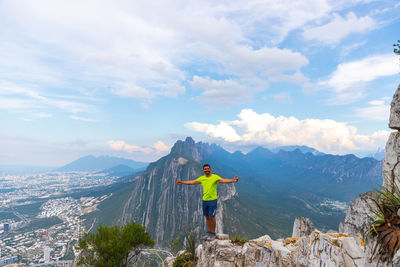 Rear view of man standing on mountain against sky