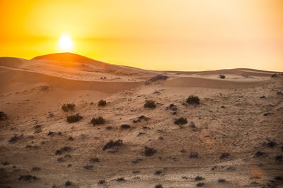 Scenic view of sand dunes against sky at sunset