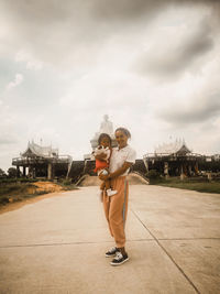 Full length of mum and daughter infront of an temple against sky