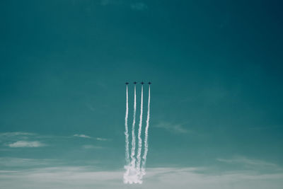 Low angle view of airplanes flying against blue sky