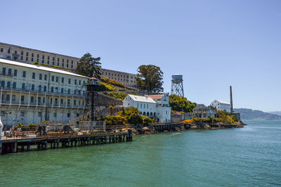 Buildings at waterfront against blue sky