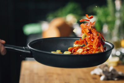 Vegetarian restaurant cooking - frying sliced red bell pepper in pan
