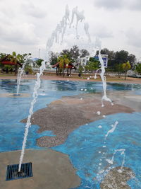 Fountain in swimming pool against sky