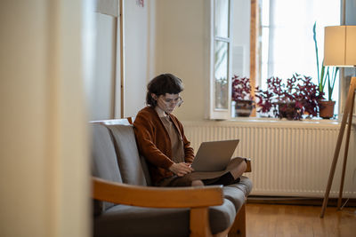 Concentrated teen girl working, studying at home in comfortable conditions using laptop computer