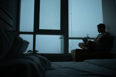 Depressed man sitting by window at home