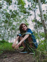 Portrait of young woman sitting on land