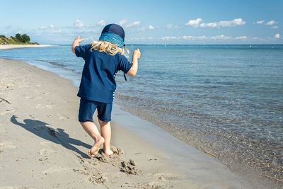 Full length of boy on beach against sky