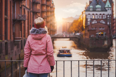 Rear view of woman standing by railing in city during winter