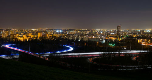 High angle view of illuminated city by buildings at night